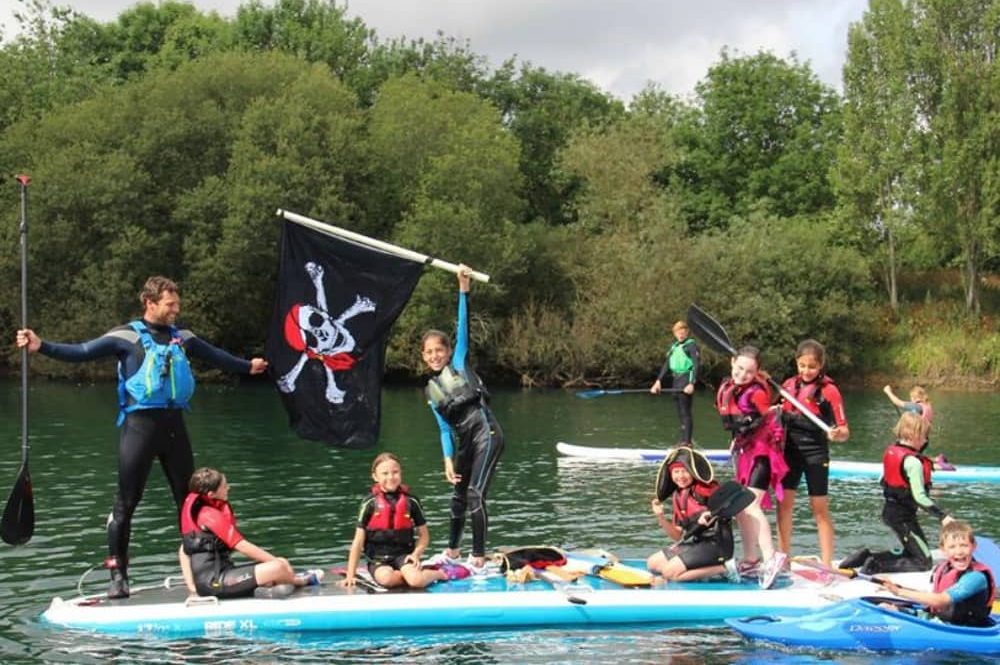 Bray Lake Watersports kids paddle boarding with jolly roger flag