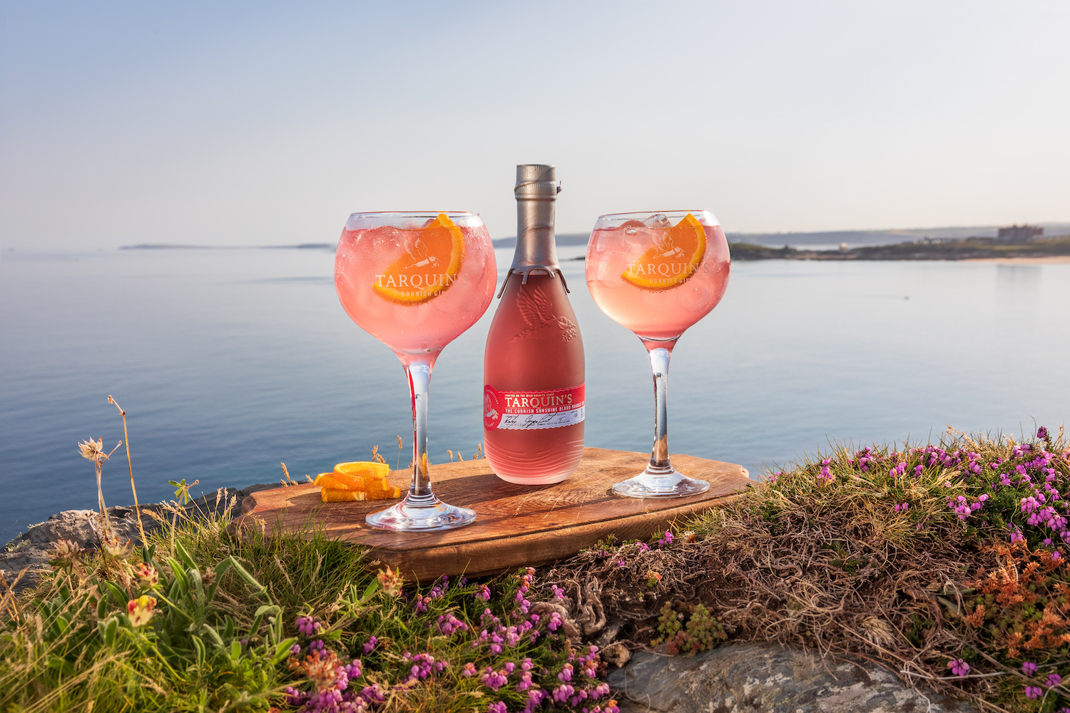 pink Tarquins gin in glasses with bottle in front of sea Southwestern Distillery Cornwall