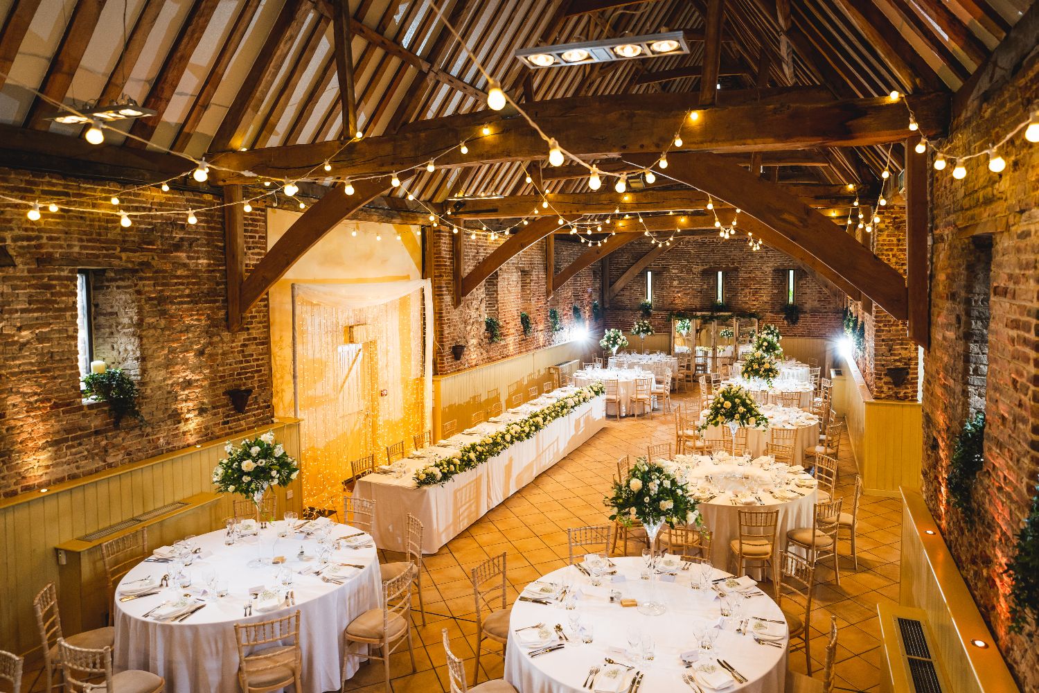 inside a wedding barn with fairy lights and beams